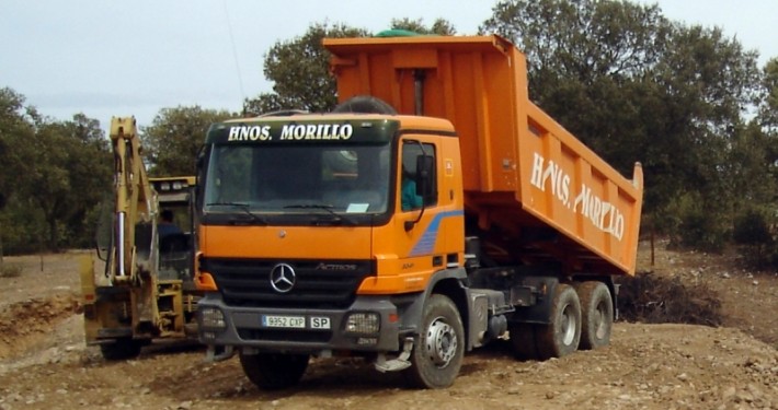 Miniexcavadora y camión volquete realizando trabajo de movimiento de tierra