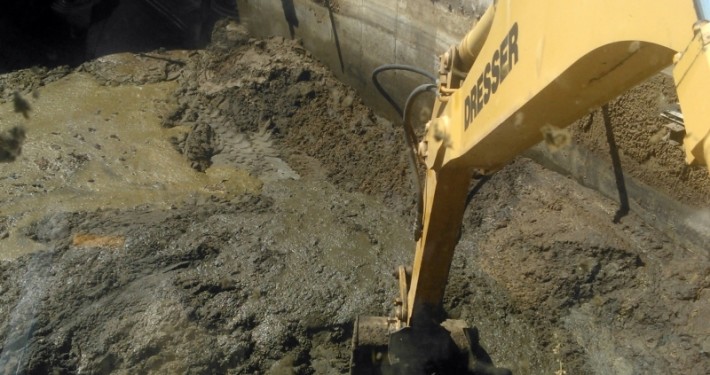 excavadora giratoria vaciando una fosa de lodos